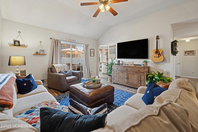 living area featuring a ceiling fan, a textured ceiling, wood finished floors, baseboards, and vaulted ceiling