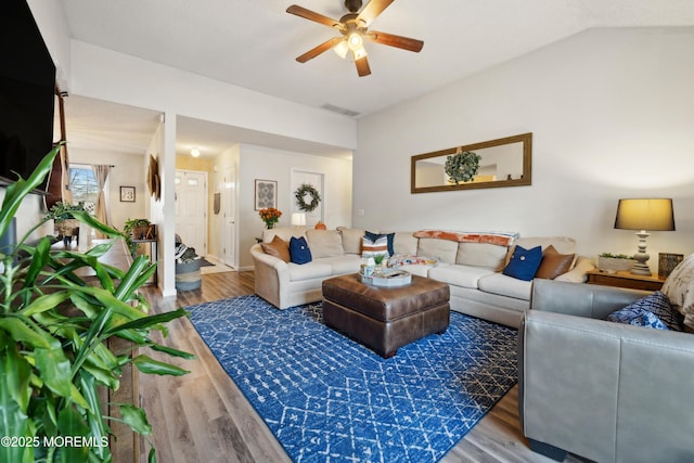 living area with vaulted ceiling, visible vents, a ceiling fan, and wood finished floors