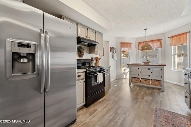 kitchen featuring light wood finished floors, under cabinet range hood, stainless steel fridge, gas stove, and a textured ceiling