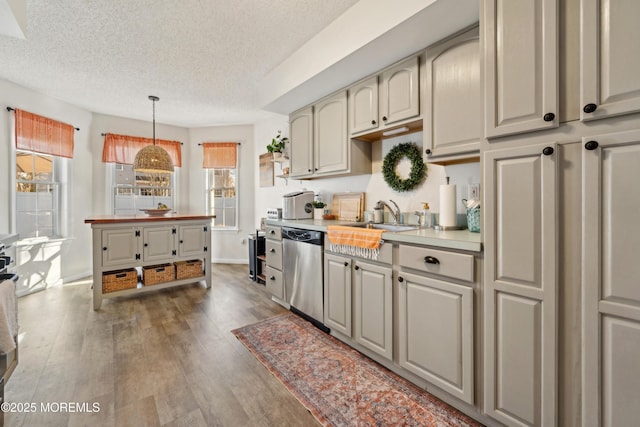 kitchen with wood finished floors, a sink, light countertops, a textured ceiling, and dishwasher