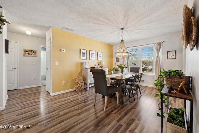 dining space with a notable chandelier, baseboards, a textured ceiling, and wood finished floors