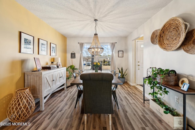 dining room with a chandelier, baseboards, a textured ceiling, and wood finished floors