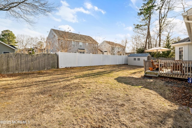 view of yard featuring a deck, an outbuilding, a storage unit, and a fenced backyard