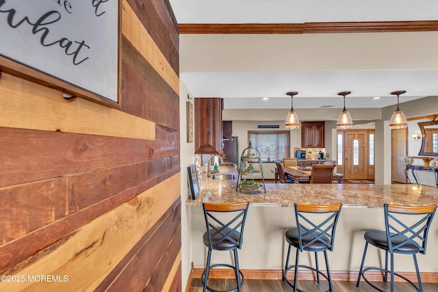 kitchen featuring decorative light fixtures, a breakfast bar, a peninsula, and a sink