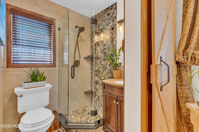 bathroom featuring vanity, tile walls, toilet, and a stall shower