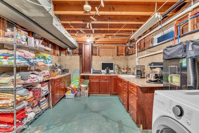 unfinished below grade area with washer / clothes dryer, concrete block wall, and a sink