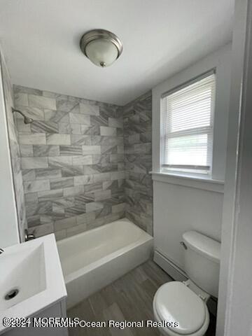 bathroom featuring washtub / shower combination, a sink, wood finished floors, and toilet