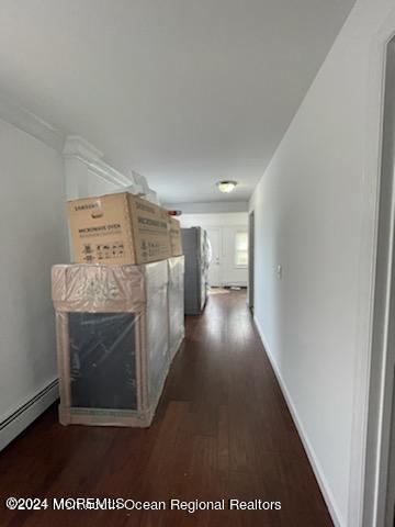 hall featuring a baseboard heating unit, dark wood-type flooring, and baseboards