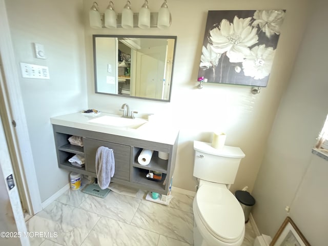 half bath featuring marble finish floor, vanity, toilet, and baseboards