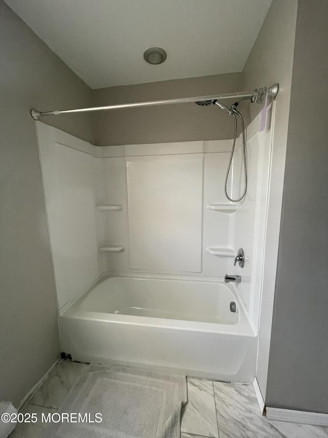 bathroom with marble finish floor, shower / washtub combination, and baseboards