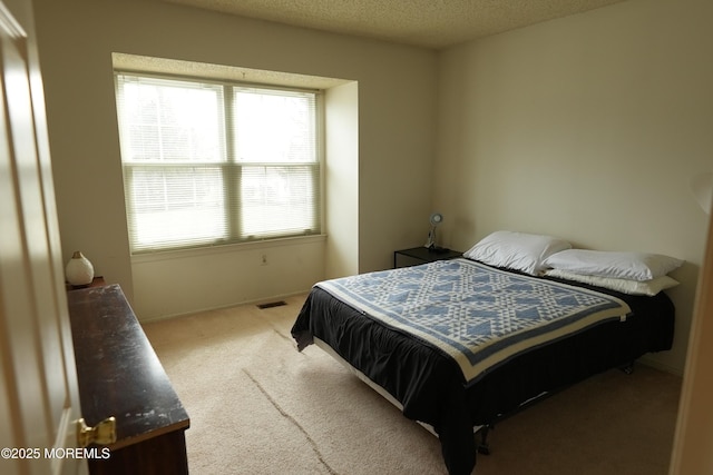 bedroom featuring carpet floors, baseboards, visible vents, and a textured ceiling