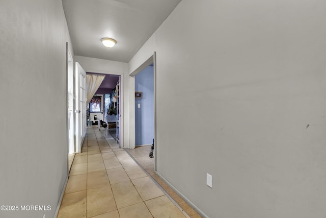 corridor with light tile patterned flooring and baseboards