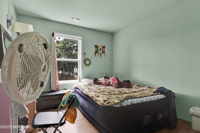 bedroom featuring wood finished floors and visible vents