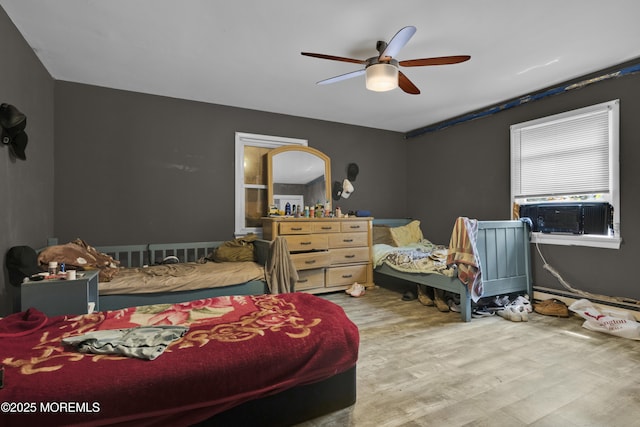 bedroom featuring ceiling fan, cooling unit, and wood finished floors