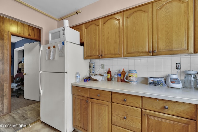 kitchen featuring brown cabinets, white appliances, light countertops, and backsplash