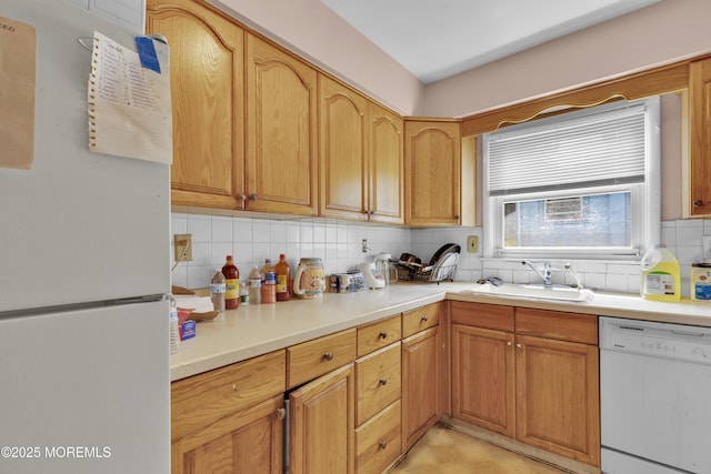 kitchen featuring light countertops, white appliances, a sink, and decorative backsplash