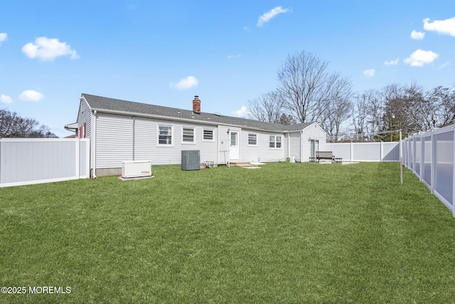 back of house with central air condition unit, entry steps, a lawn, a chimney, and a fenced backyard