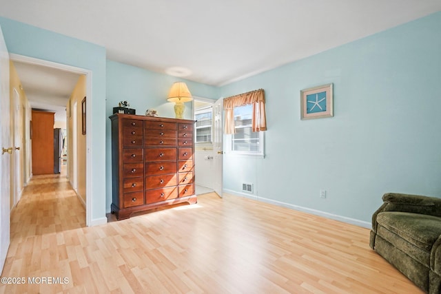 living area with light wood-style floors, visible vents, and baseboards