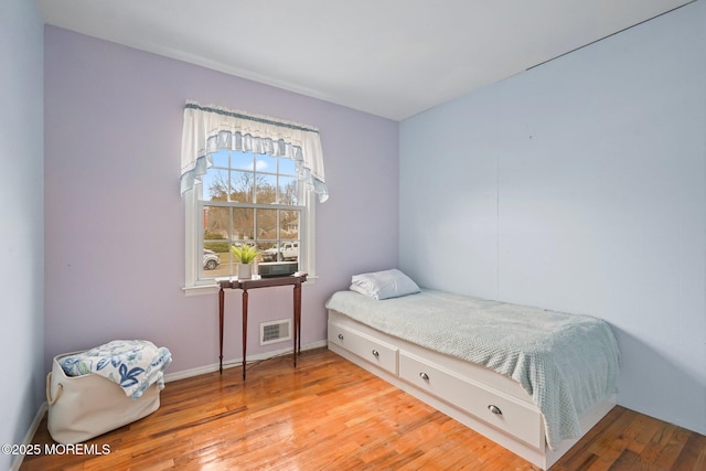 bedroom with visible vents, baseboards, and hardwood / wood-style flooring