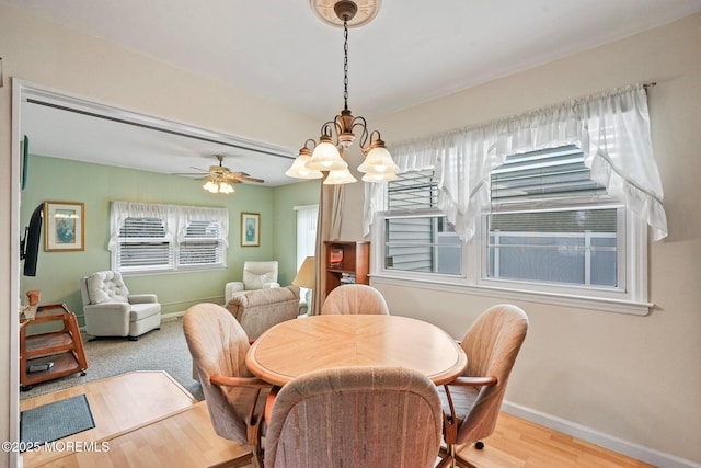 dining area with ceiling fan with notable chandelier, baseboards, and wood finished floors