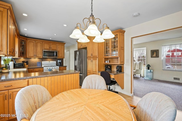 kitchen with visible vents, a sink, stainless steel appliances, glass insert cabinets, and dark countertops