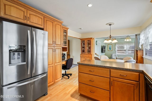 kitchen with dark countertops, stainless steel fridge, and brown cabinets