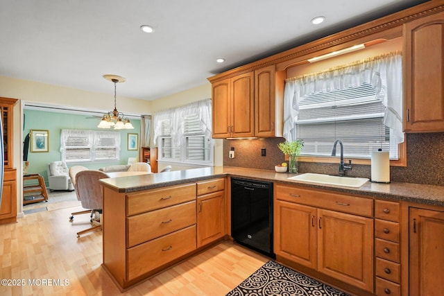 kitchen featuring a peninsula, black dishwasher, plenty of natural light, and a sink