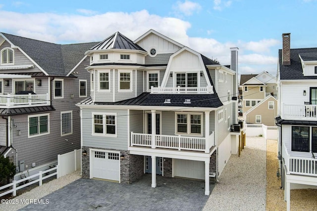 view of front facade with metal roof, a garage, stone siding, decorative driveway, and a standing seam roof