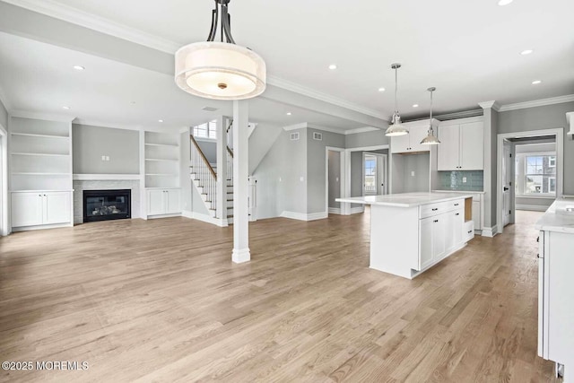 kitchen with light wood-style floors, white cabinetry, light countertops, and decorative light fixtures