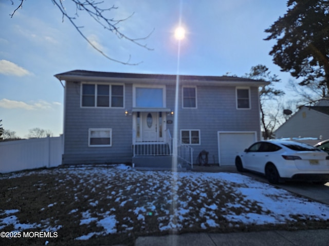 bi-level home with a garage, driveway, and fence