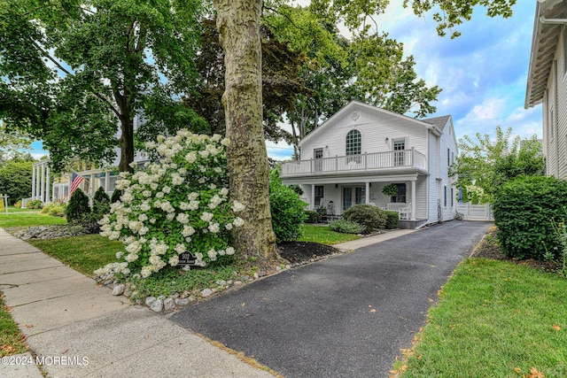 view of front of home with a balcony and a front lawn