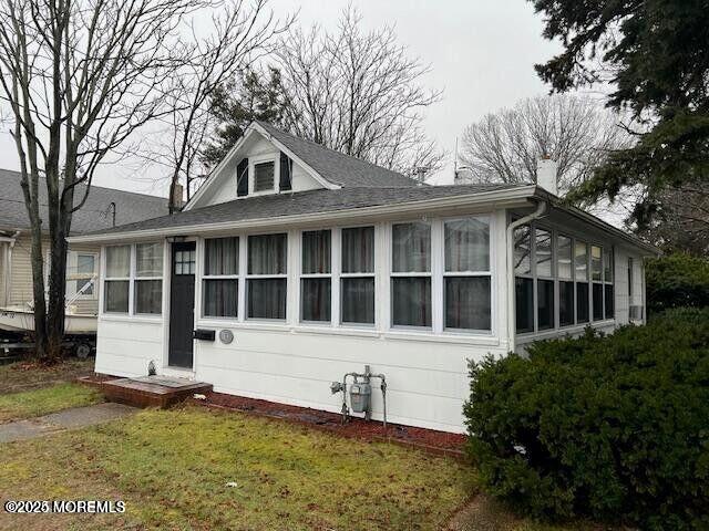 exterior space with a chimney, a front yard, and a sunroom