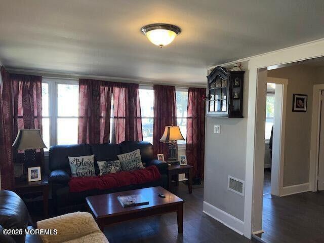 living area featuring dark wood-type flooring, visible vents, and baseboards