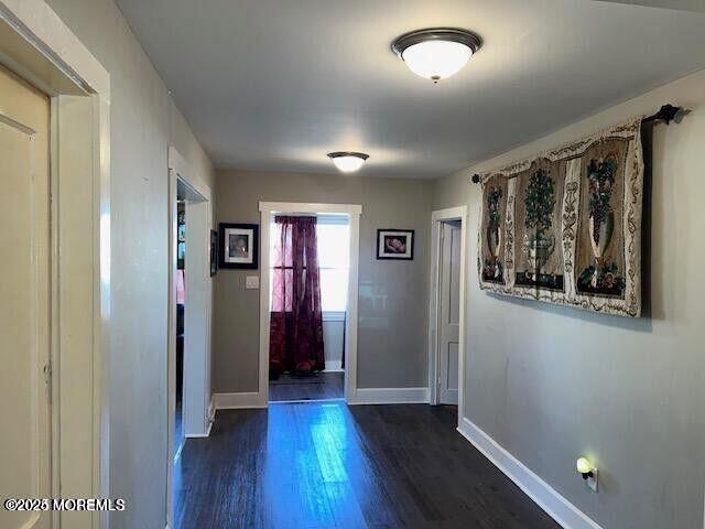 doorway featuring dark wood-style flooring and baseboards