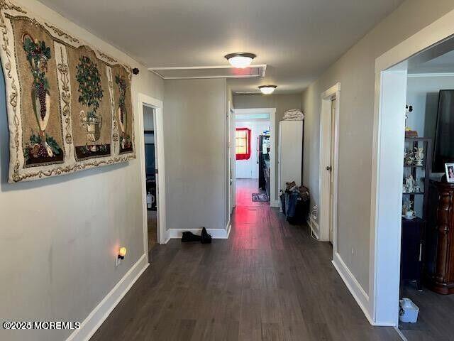 corridor with dark wood-style floors and baseboards