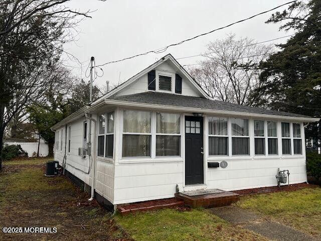 bungalow-style house with a sunroom and central AC unit