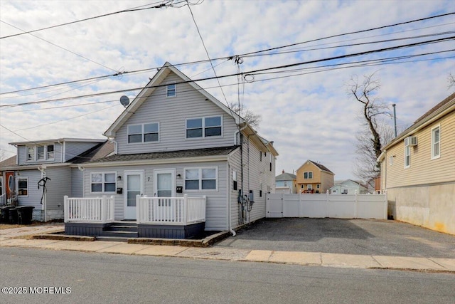 view of front facade with an AC wall unit and fence