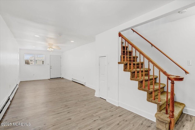 interior space featuring a baseboard radiator, stairway, a baseboard heating unit, ceiling fan, and wood finished floors