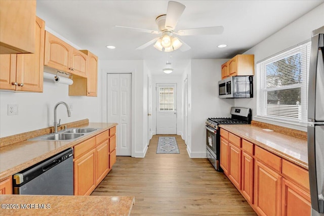 kitchen with stainless steel appliances, light countertops, light wood-type flooring, light brown cabinets, and a sink