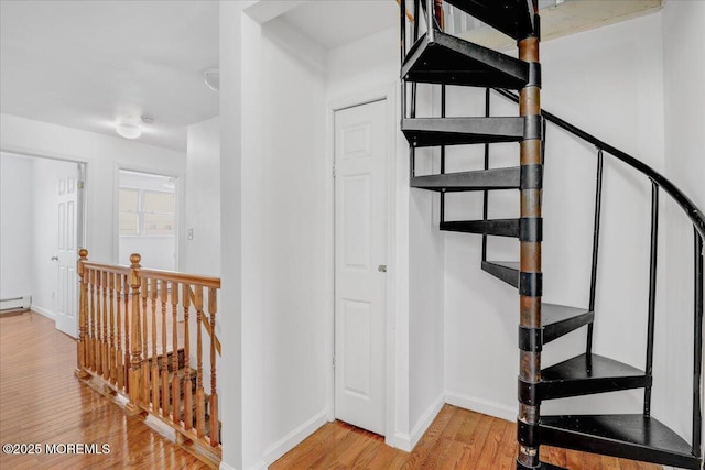 stairs with baseboard heating, baseboards, and wood finished floors