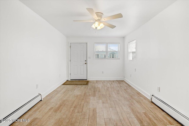 spare room with a ceiling fan, baseboard heating, light wood-style flooring, and baseboards