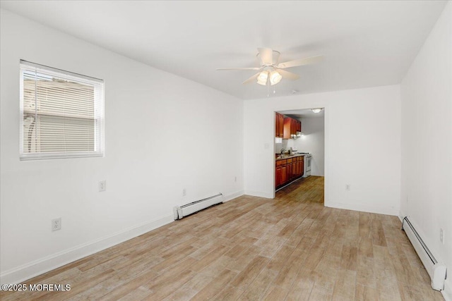 spare room with baseboards, baseboard heating, a ceiling fan, and light wood-style floors