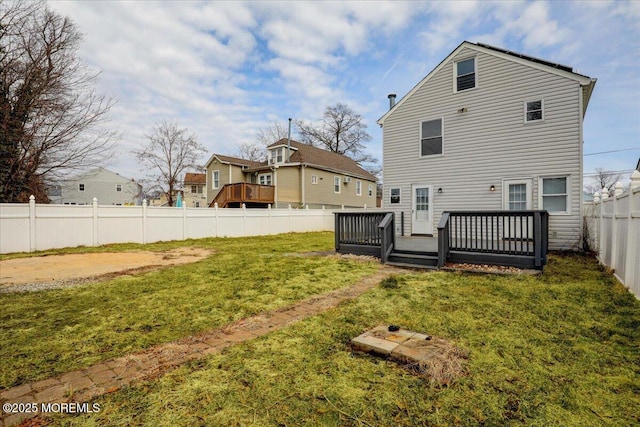 back of property with a deck, a lawn, and a fenced backyard