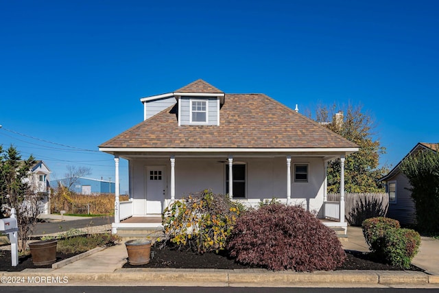 bungalow-style house featuring a shingled roof, a porch, and stucco siding