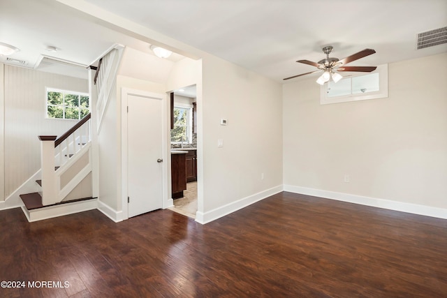 unfurnished room featuring stairs, visible vents, dark wood finished floors, and a ceiling fan