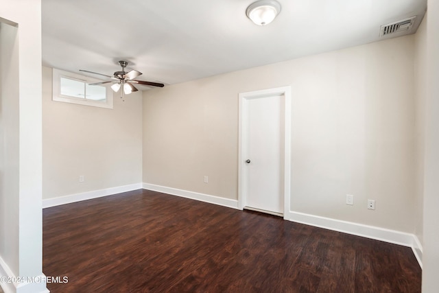 empty room with dark wood-type flooring, a ceiling fan, visible vents, and baseboards