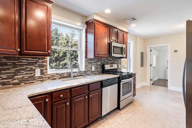 kitchen with light tile patterned floors, stainless steel appliances, visible vents, backsplash, and a sink