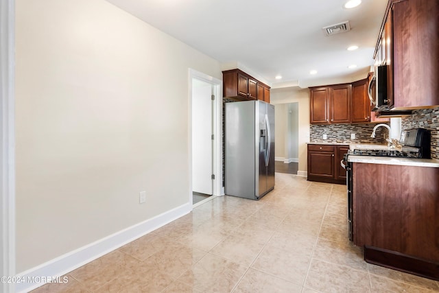 kitchen featuring stainless steel appliances, visible vents, baseboards, light countertops, and backsplash