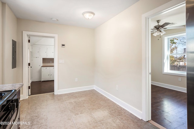 empty room featuring a ceiling fan, electric panel, baseboards, and light tile patterned floors