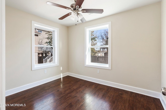 empty room with dark wood-type flooring, baseboards, and a ceiling fan